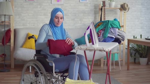 Woman in Wheelchair Doing Laundry in Home