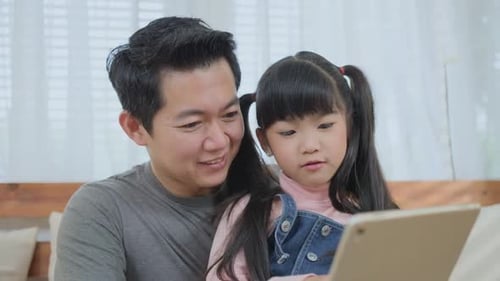 Father and Daughter Using Tablet Together Indoors