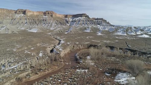 Flying over winding river in the desert with snow