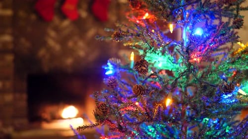 Ein festlicher Weihnachtsbaum mit bunten Lichtern und Ornamenten vor einem Feuer mit Strumpf