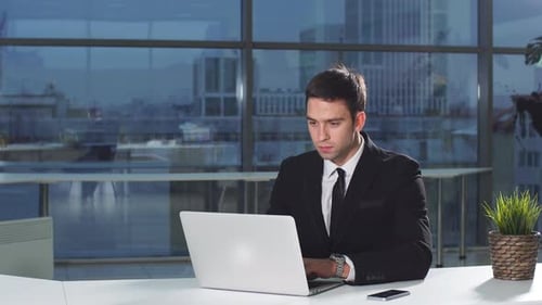 Businessman in Office with Laptop Computer