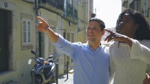 Happy Couple Hugging and Pointing Up While Walking on Street