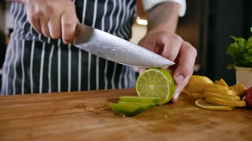 Close-up Man Chef Cuts Fresh Fruits Lemon and Lime on Wooden Cutting Board