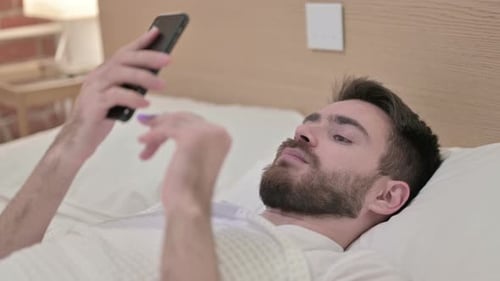 Man Lying in Bed Using Smartphone