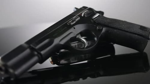 Black Handgun with Bullets on Reflective Surface