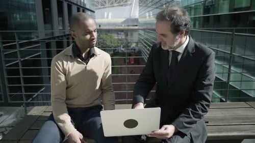 Positive Confident Businessmen Sitting Between City Buildings