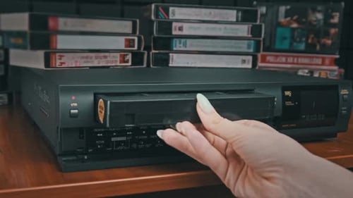 Hand Inserts VHS Tape Into VCR Machine