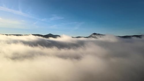 Aerial View of Forward Movement Over White Puffy Clouds in Wide Mountain Valley