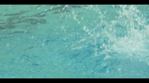 Swimmer dives into swimming pool creating splashes