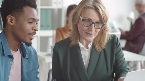 Experienced Female Manager Mentoring Afro-American Male Trainee in Office