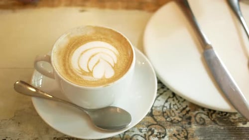 eine Tasse Late Coffee mit Blumenform oben drauf im Cafe