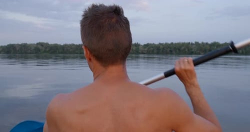 A Man Kayaks on a Calm River