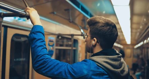Man riding subway train holding onto railing