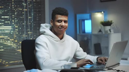 Smiling Man Working on Laptop at Night