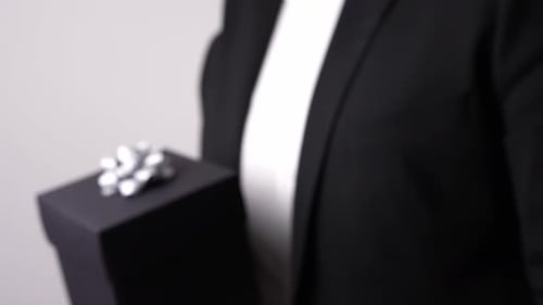 Person in Suit Holding Gift with Silver Bow