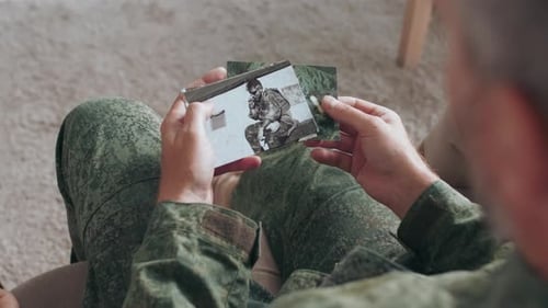 Soldier Looking at Old Photos Indoors