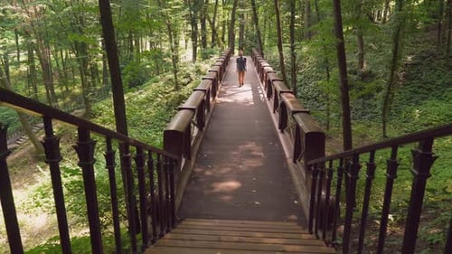 Ein junger Mann geht auf einer Brücke im Park und geht nach oben