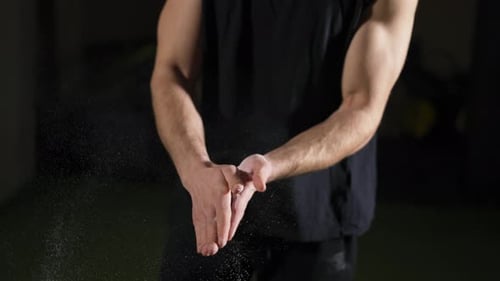 Unrecognizable Male Athlete Rubbing and Clapping Chalk at Gym