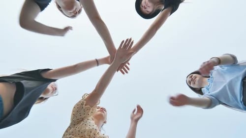 Young Women Join Hands in Team Huddle