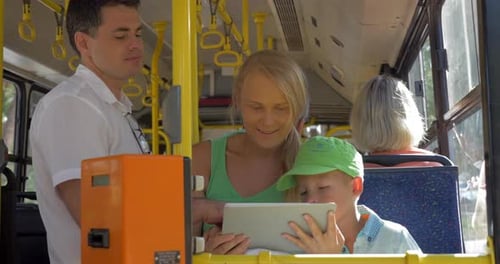 Family Rides Public Transport Bus, Using Tablet