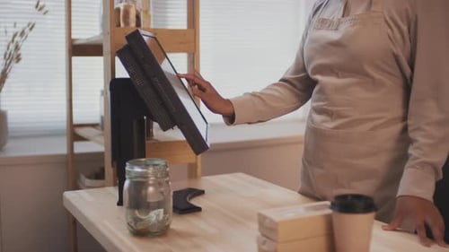 Worker Uses Point-of-Sale Touchscreen at Store Counter