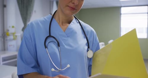 Caucasian female doctor holding medical documentation, smiling to camera in hospital room
