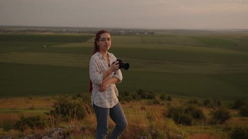 Woman Photographer Posing on Rural Hill at Sunset