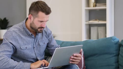 Man Working on Laptop Sitting on Couch Indoors