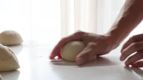 Hands Kneading Dough on a White Countertop