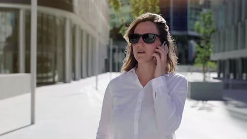 businesswoman talking on cellphone with walking city street.