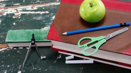 Green apple on book stack with school supplies