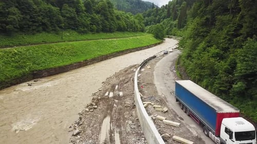 aerial flight over the mountain river black yew in Ukraine Carpathians, near the road on which a tru