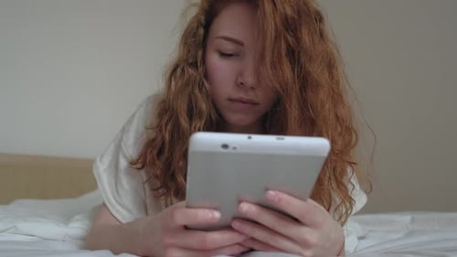 Young Woman Using Tablet in Bed Indoors