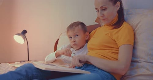 Cozy Mother Reading Bedtime Story to Little Boy