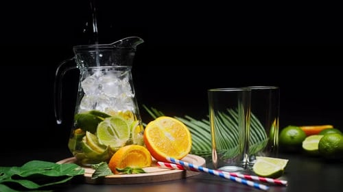 Pouring Refreshing Citrus Beverage with Lime and Orange