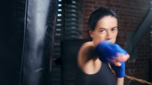 Woman Boxer Punches Heavy Bag in Gym