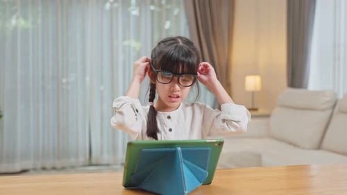 Girl Using Tablet at Home Puts on Glasses