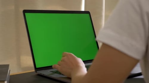 Over the shoulder shot of Asian woman looking at green screen. Office person using laptop