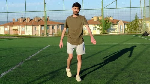 Young Man Stretching on a Green Field
