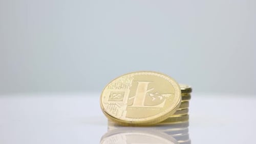 Goldene Litecoins gestapelt auf grauem Hintergrund.