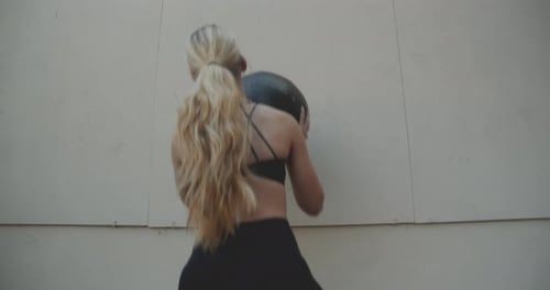 Young Woman Squatting To Throw And Catch Medicine Ball