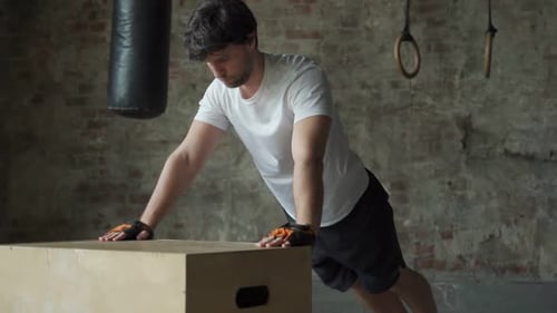 A Man Working Out in the Gym Does Pushups From a Wooden Box