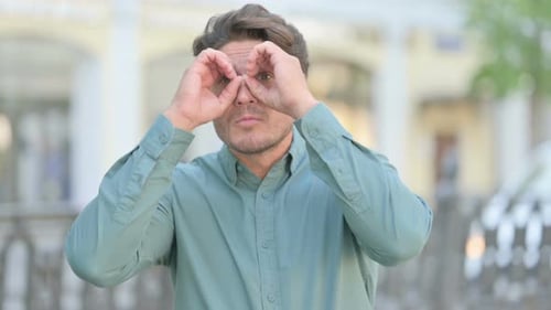 Man Makes Binocular Shape with Hands, then Smiles