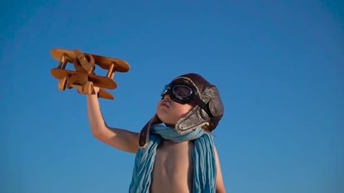 Child Pilot Flying Wooden Airplane, Blue Sky Backdrop