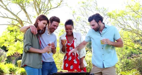 Happy friends preparing a barbecue grill in park