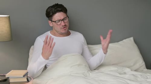 Man Talking in Bed Wearing Glasses