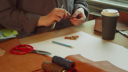 An Experienced Tailor in the Workshop Behind the Workbench Prepares Accessories for Creating a