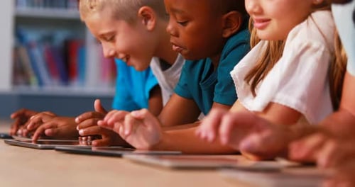 Crianças em idade escolar usando tablet digital na biblioteca