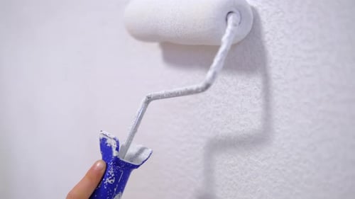 White Paint Roller Applying Paint to Wall