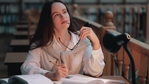 Woman Studying in Library Taking Notes